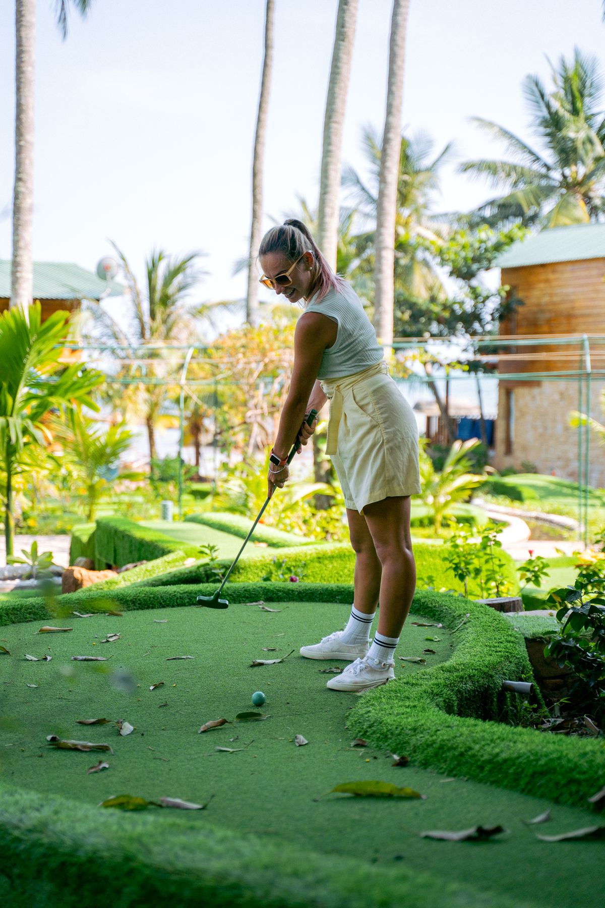 A smiling player lining up a putt on a mini golf course