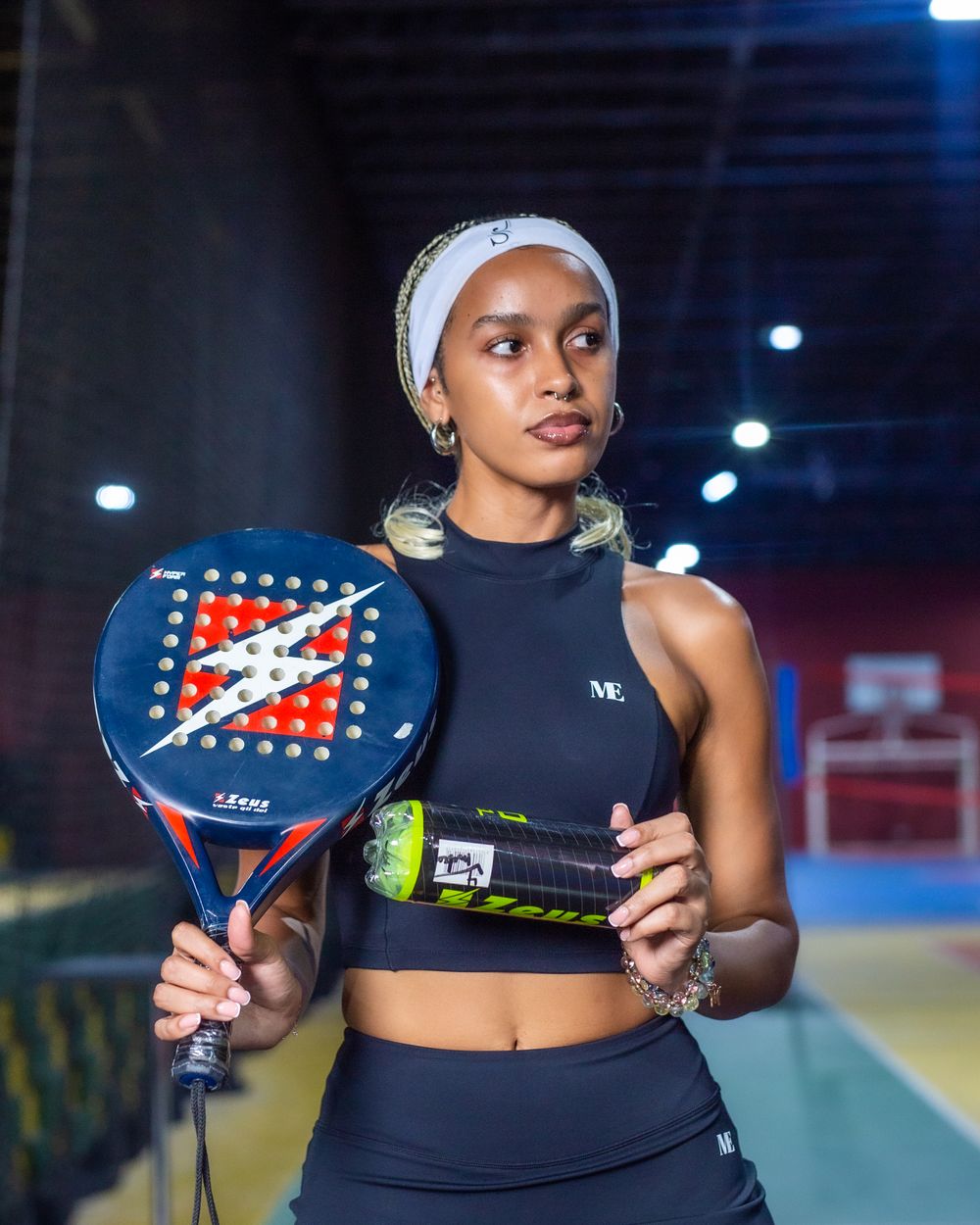 A player on an indoor padel court holding a racket and ball