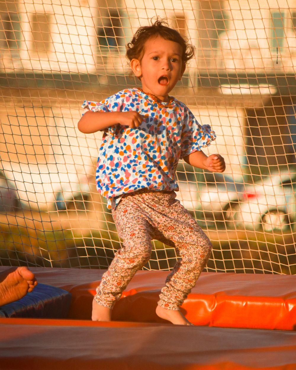 A child jumping with both feet off a trampoline, mid-air and smiling